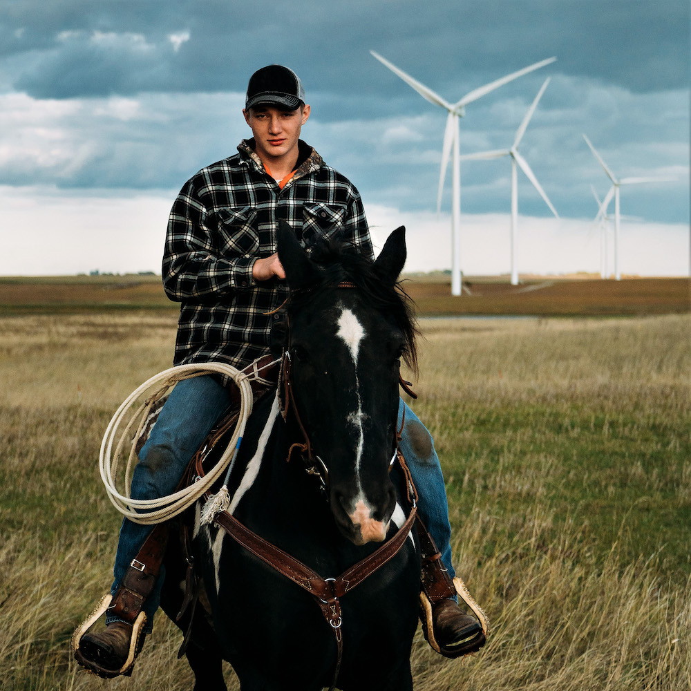 Man on horse in field with wind turbines