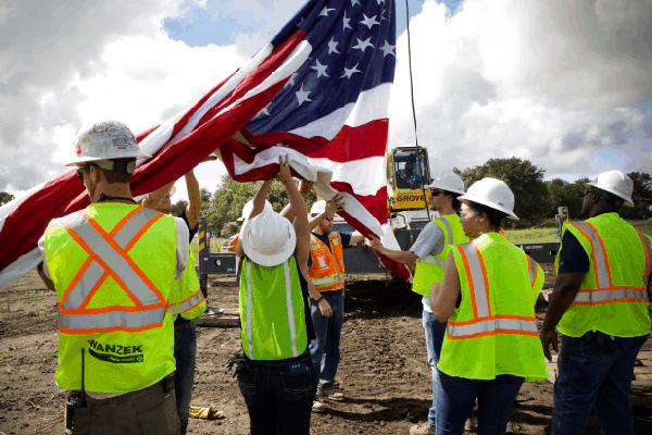 People with construction clothing raising the American flag