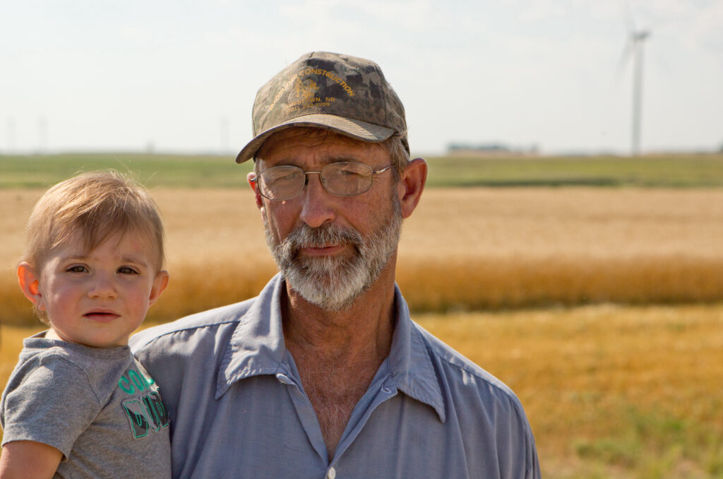 Farmer and child in field with wind turbines