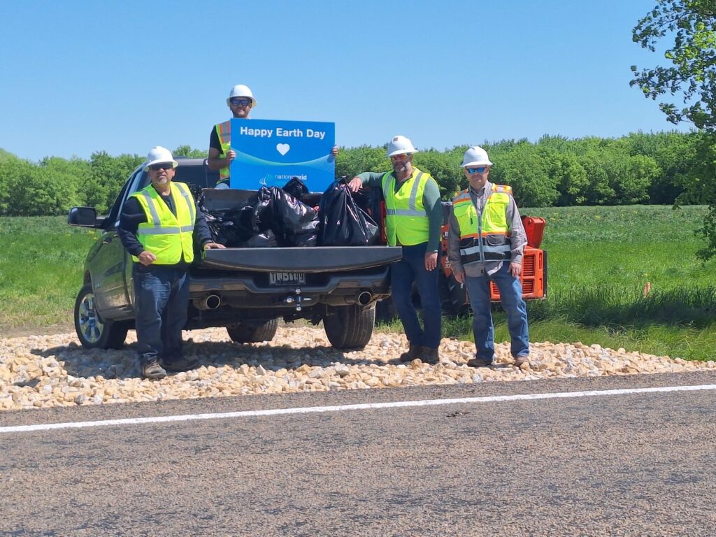 People with Happy Earth Day sign and trash bags on side of road