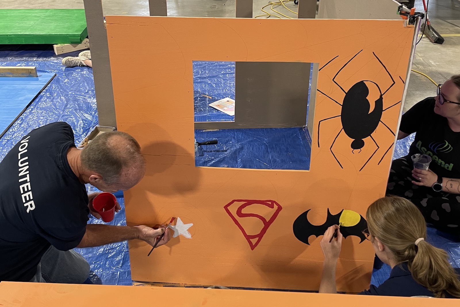 Team members painting a playhouse